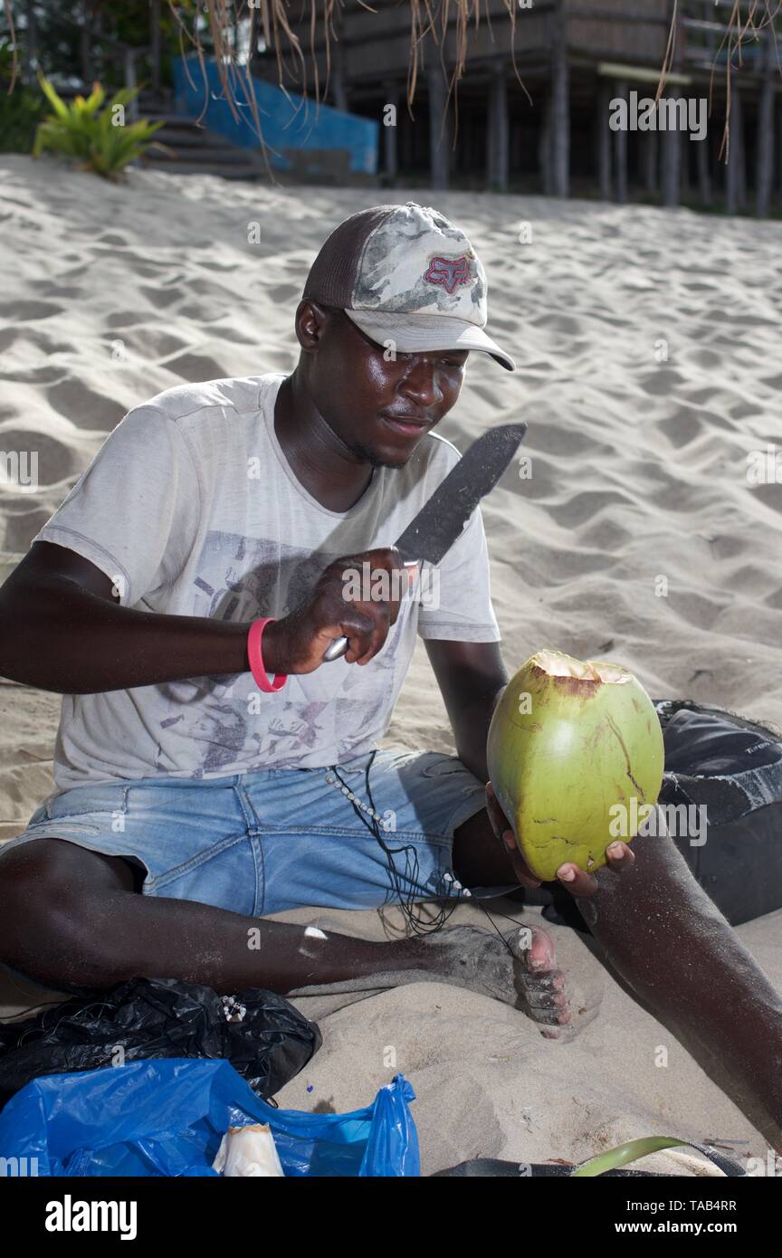 Uomo locale preparando un cocounut su Tofo beach, Mozambico Foto Stock