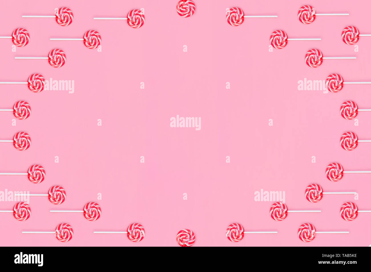 Cornice rotonda dei lecca lecca con strisce rosse e bianche su sfondo rosa. Foto Stock