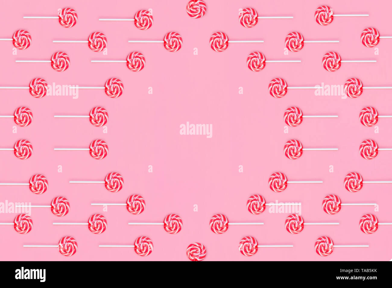 Cornice rotonda dei lecca lecca con strisce rosse e bianche su sfondo rosa. Foto Stock