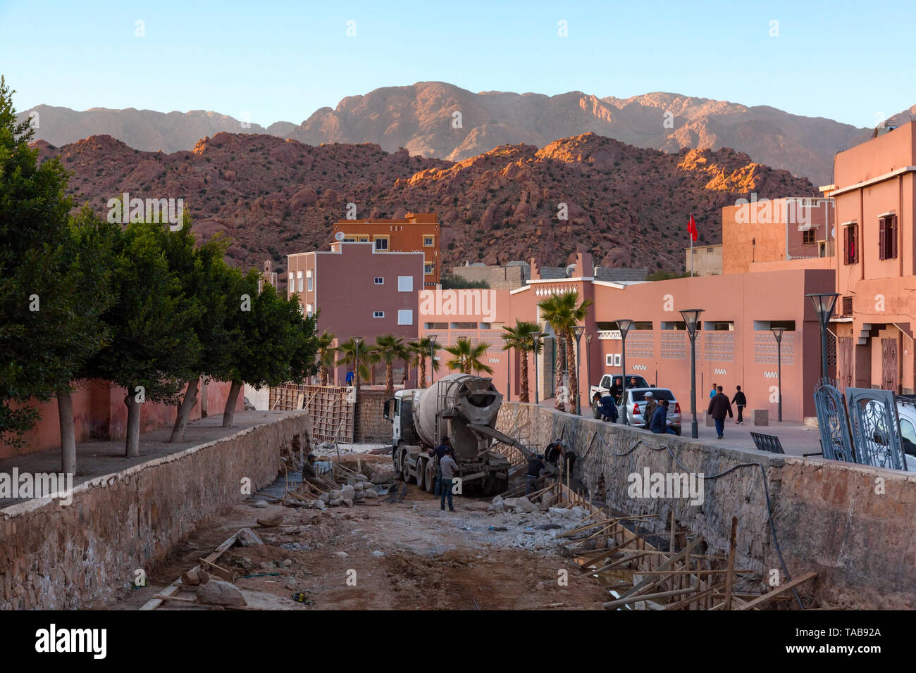 Lavoratori edili riparazione di un canale con l'Anti-Atlas montagne in distanza. Tafraoute, Tiznit Provincia, Souss-Massa, Marocco, Africa. Foto Stock