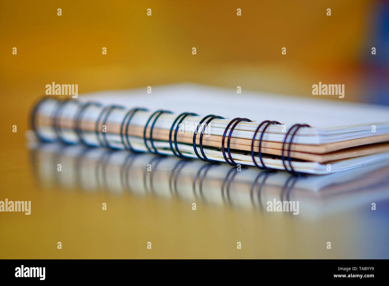 A spirale, notebook su un dorato e sfondo blu con la riflessione. Lavorare in ufficio. La ricerca e la formazione. Profondità di campo. Foto Stock