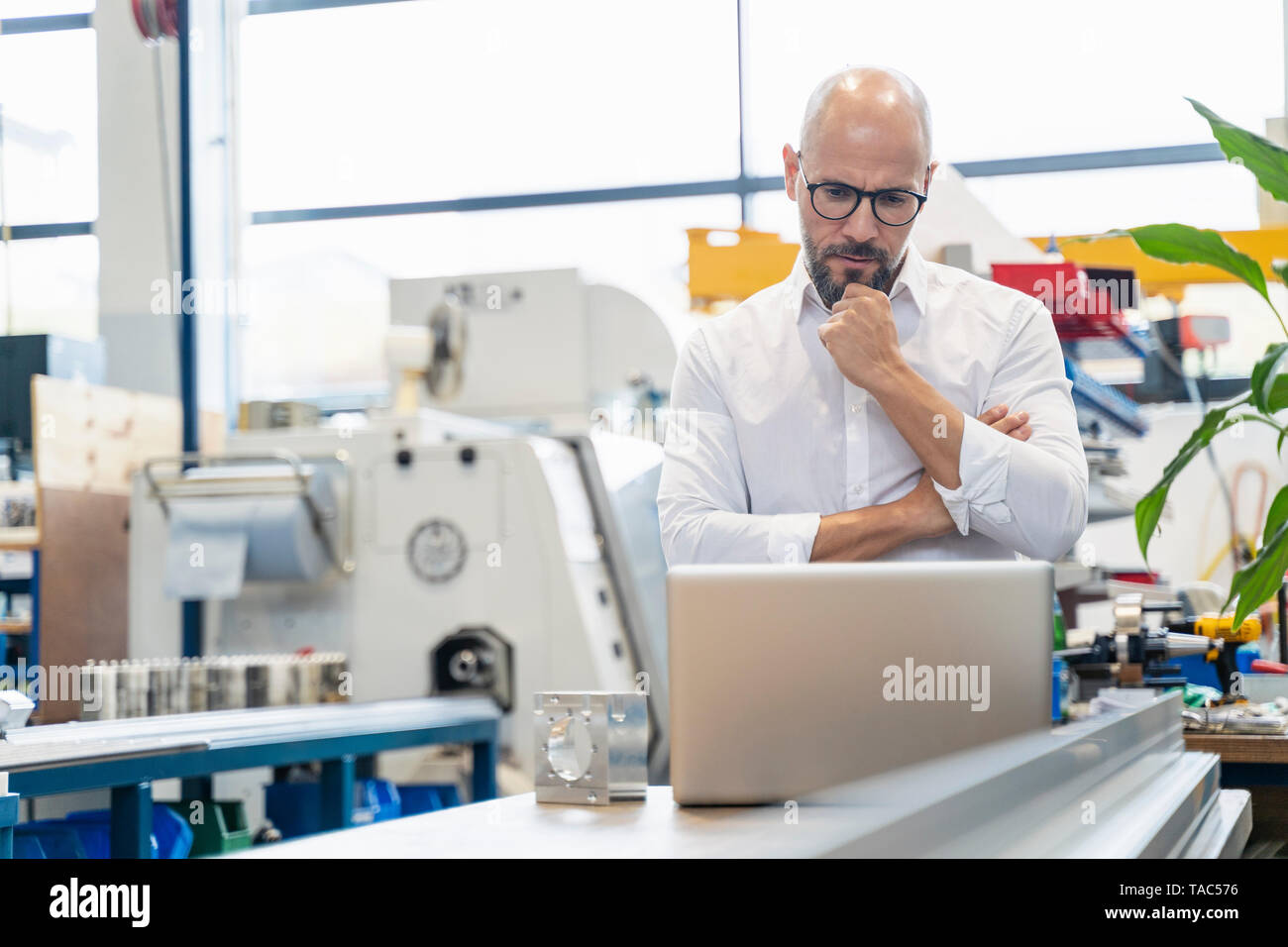 Imprenditore focalizzato utilizzando laptop in fabbrica Foto Stock