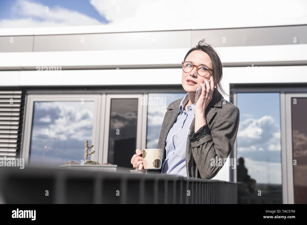 Imprenditrice sul telefono cellulare sulla terrazza sul tetto Foto Stock