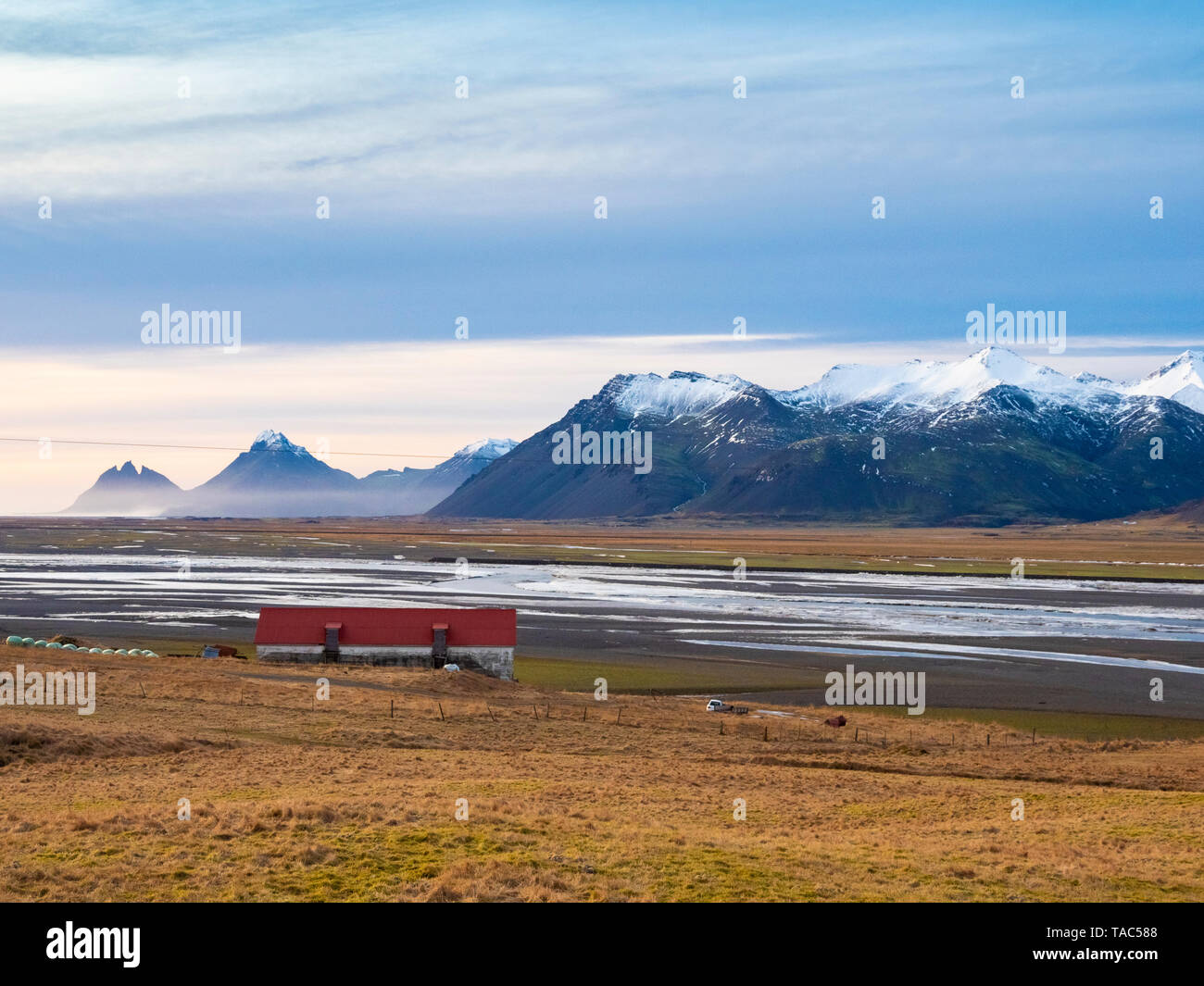 L'Islanda, Austurland, paesaggio con casa sulle montagne e sul modo per Egilsstadir Foto Stock