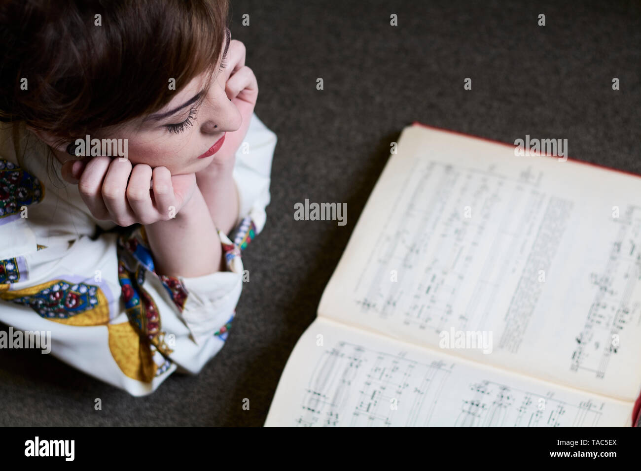 Studentessa la lettura di un libro di musica in una biblioteca pubblica Foto Stock