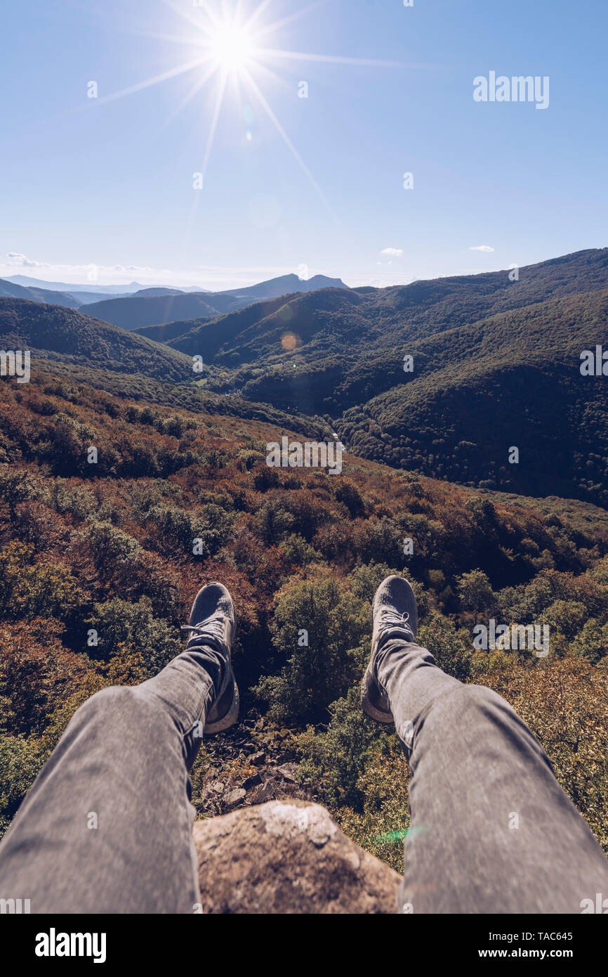 Spagna, Navarra, foresta di Irati, uomo di gambe penzolanti sopra paesaggio forestale in controluce Foto Stock