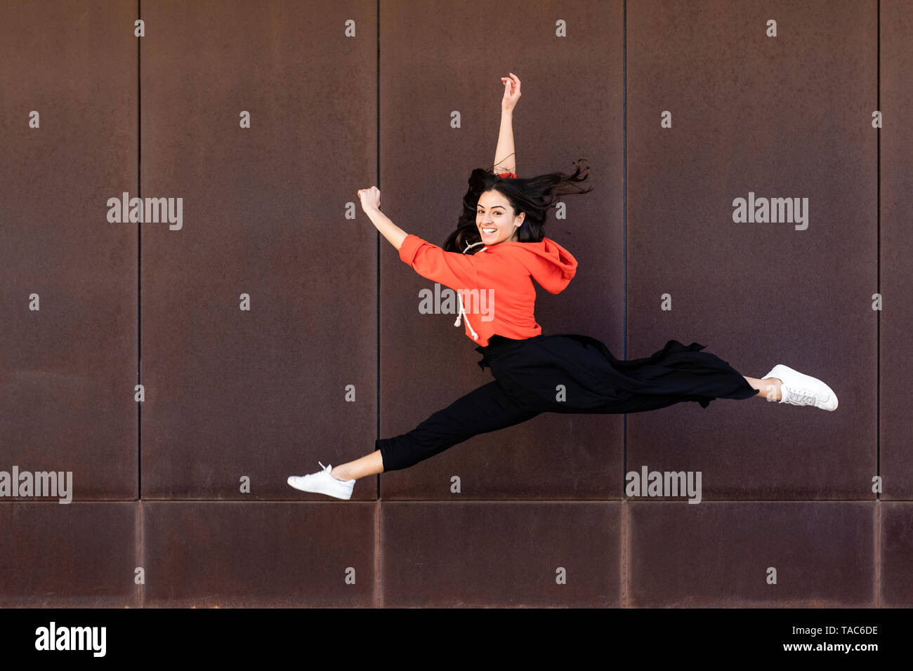 Giovane ballerino di danza contemporanea di fronte ad una parete arrugginito a saltare e ballare, guardando la fotocamera Foto Stock