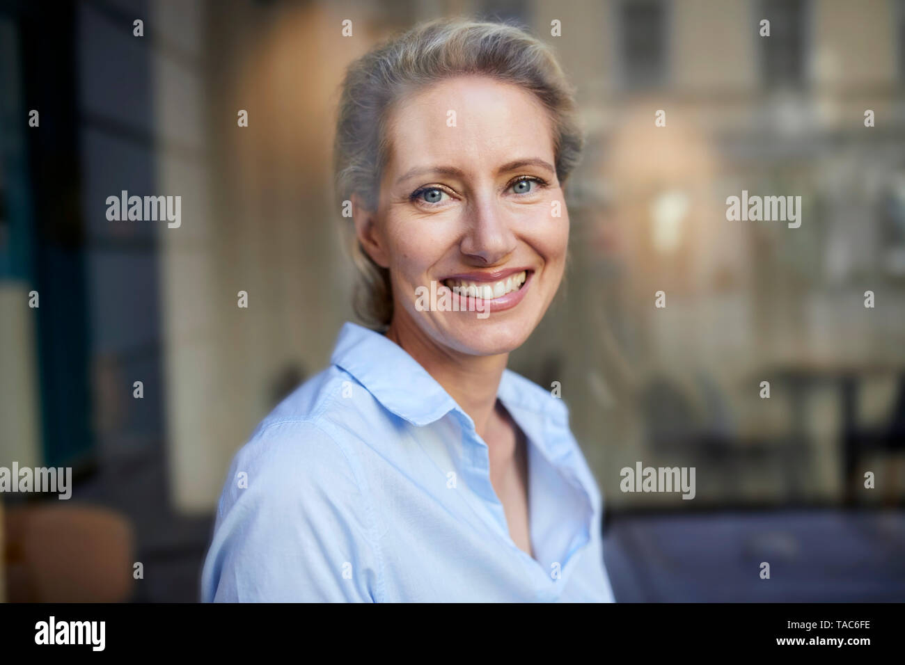 Ritratto di donna sorridente dietro il vetro di finestra Foto Stock