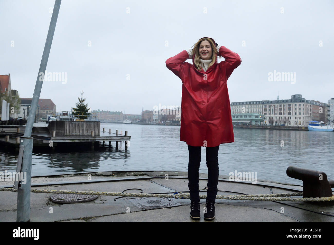 Danimarca, Copenaghen, donna felice al waterfront in condizioni di tempo piovoso Foto Stock