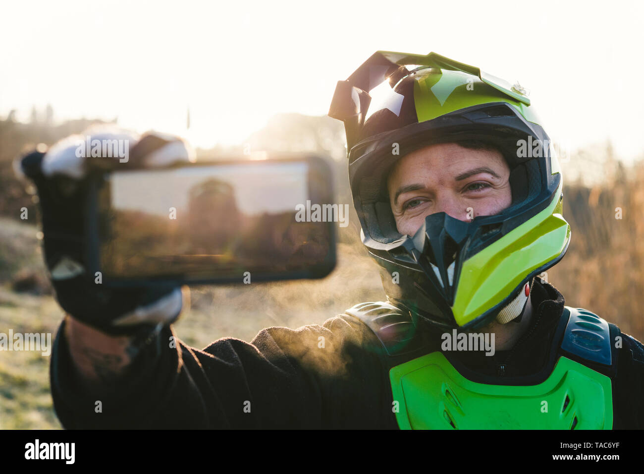 Ritratto di driver di motocross prendendo un selfie al tramonto Foto Stock