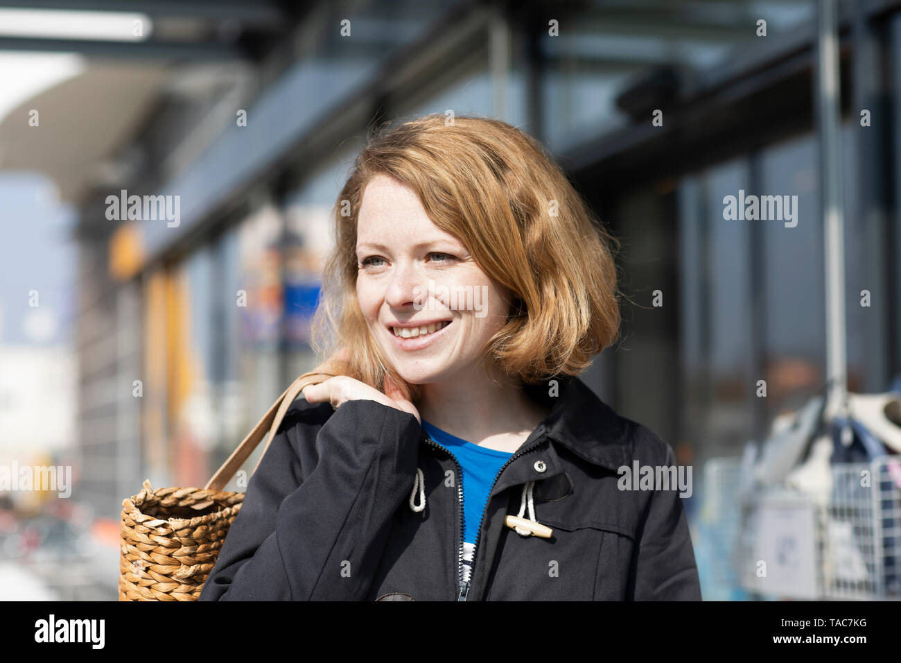 Ritratto di donna sorridente con borsa da shopping di fronte supermercato Foto Stock