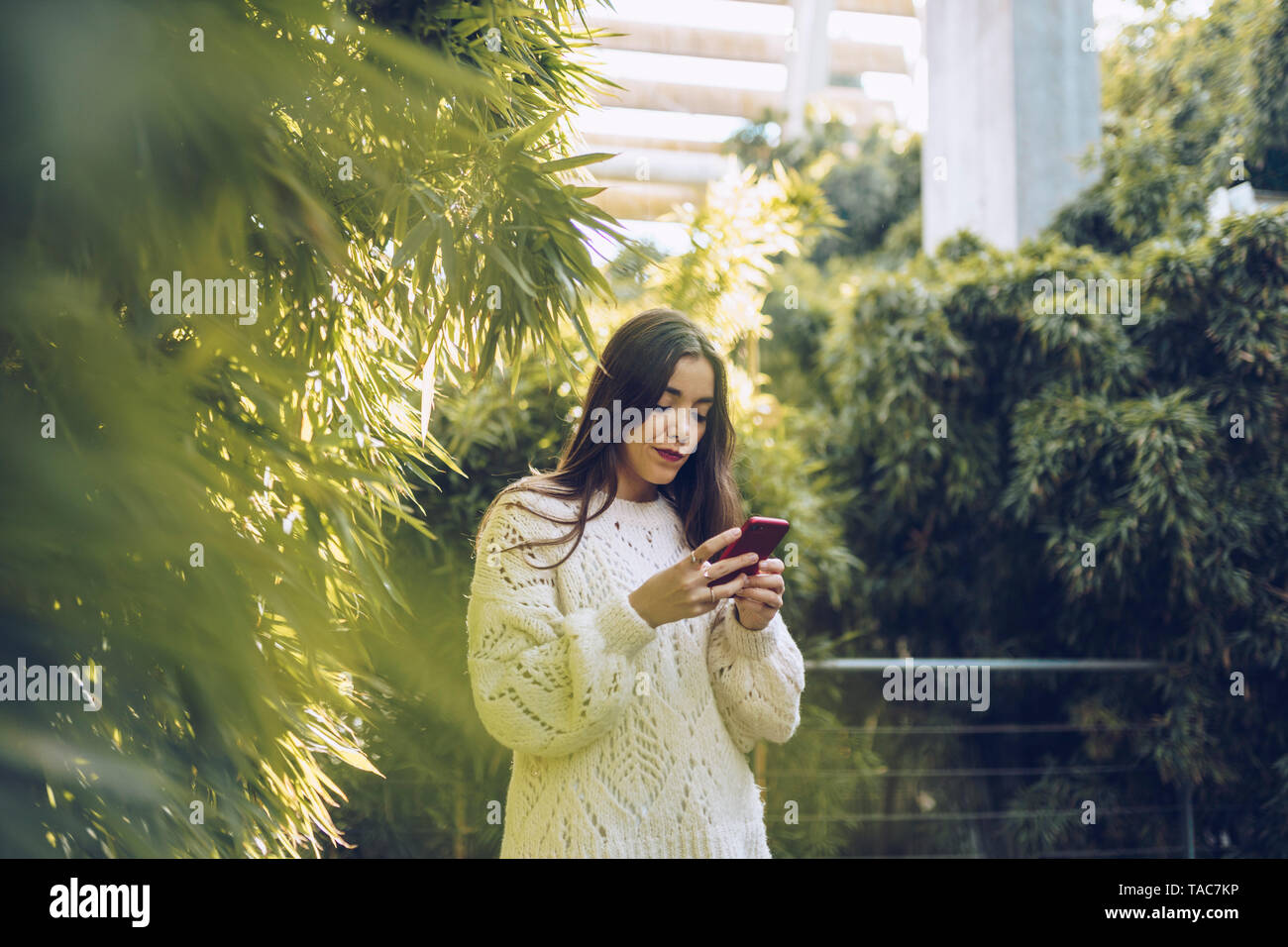 Giovane donna utilizzando il cellulare in un parco Foto Stock