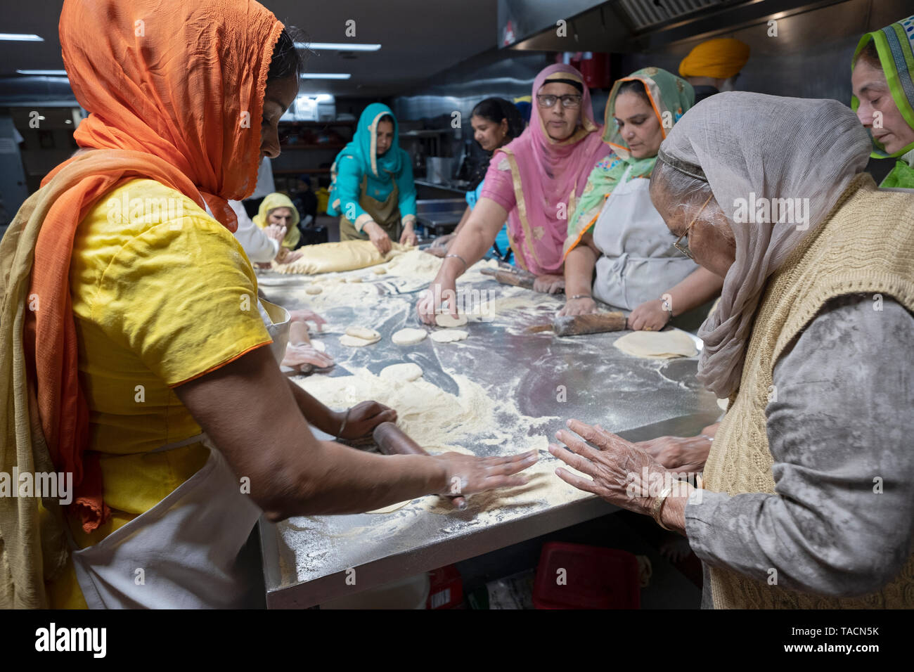 La religione sikh le donne di tutte le età preparare roti pane per il loro tempio della langar (gratuita cucina). A sud delle colline di Richmond, Queens, a New York City. Foto Stock