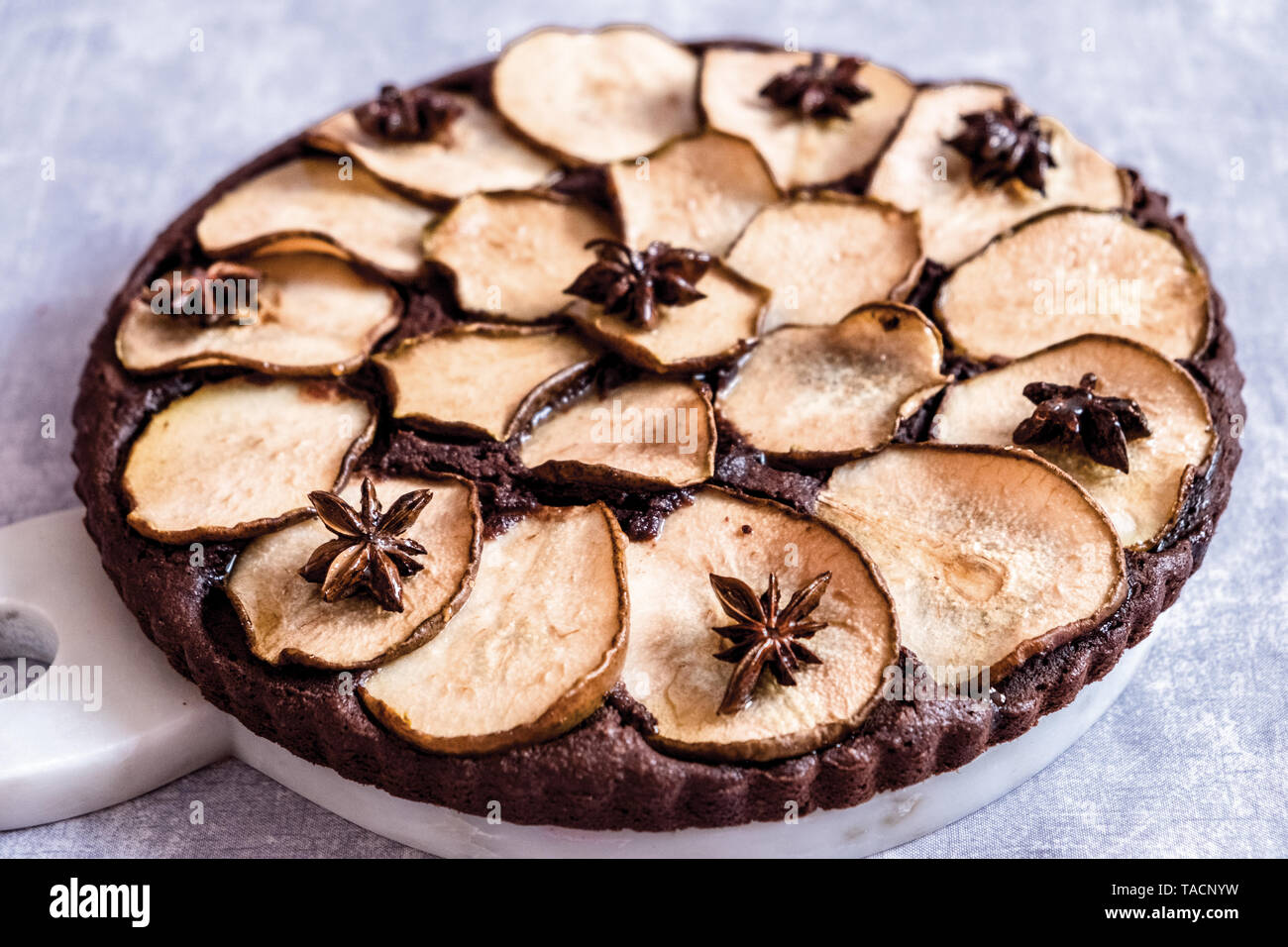 Cioccolato mandorle Pera Frangipane crostata con anice stellato su uno sfondo grigio chiaro Foto Stock