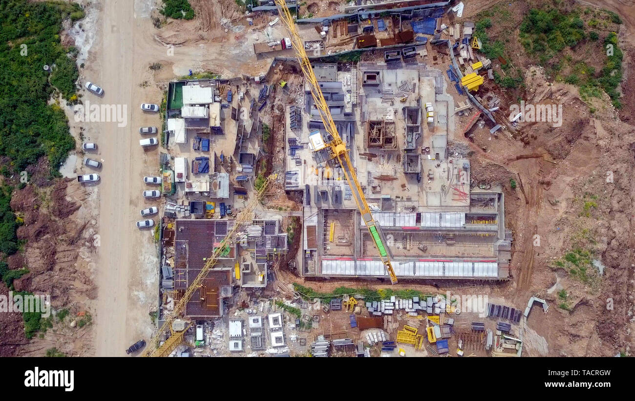 Sito in costruzione - immagine aerea di una grande zona residenziale composto durante le prime fasi di costruzione, con gru e verde ambiente circostante. Foto Stock