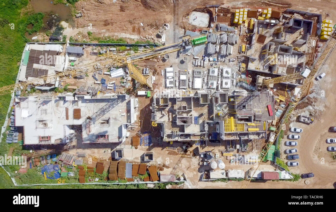 Sito in costruzione - immagine aerea di una grande zona residenziale composto durante le prime fasi di costruzione, con gru e verde ambiente circostante. Foto Stock