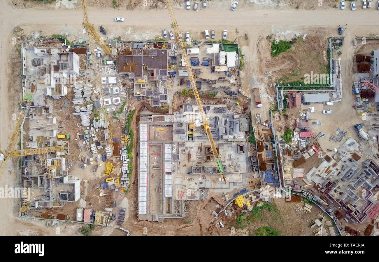 Sito in costruzione - immagine aerea di una grande zona residenziale composto durante le prime fasi di costruzione, con gru e verde ambiente circostante. Foto Stock