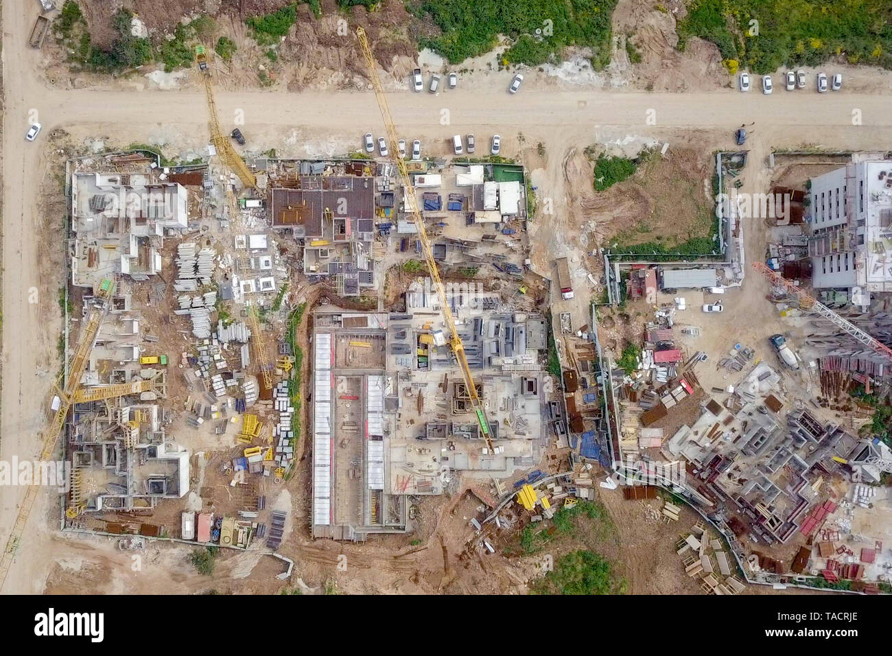 Sito in costruzione - immagine aerea di una grande zona residenziale composto durante le prime fasi di costruzione, con gru e verde ambiente circostante. Foto Stock