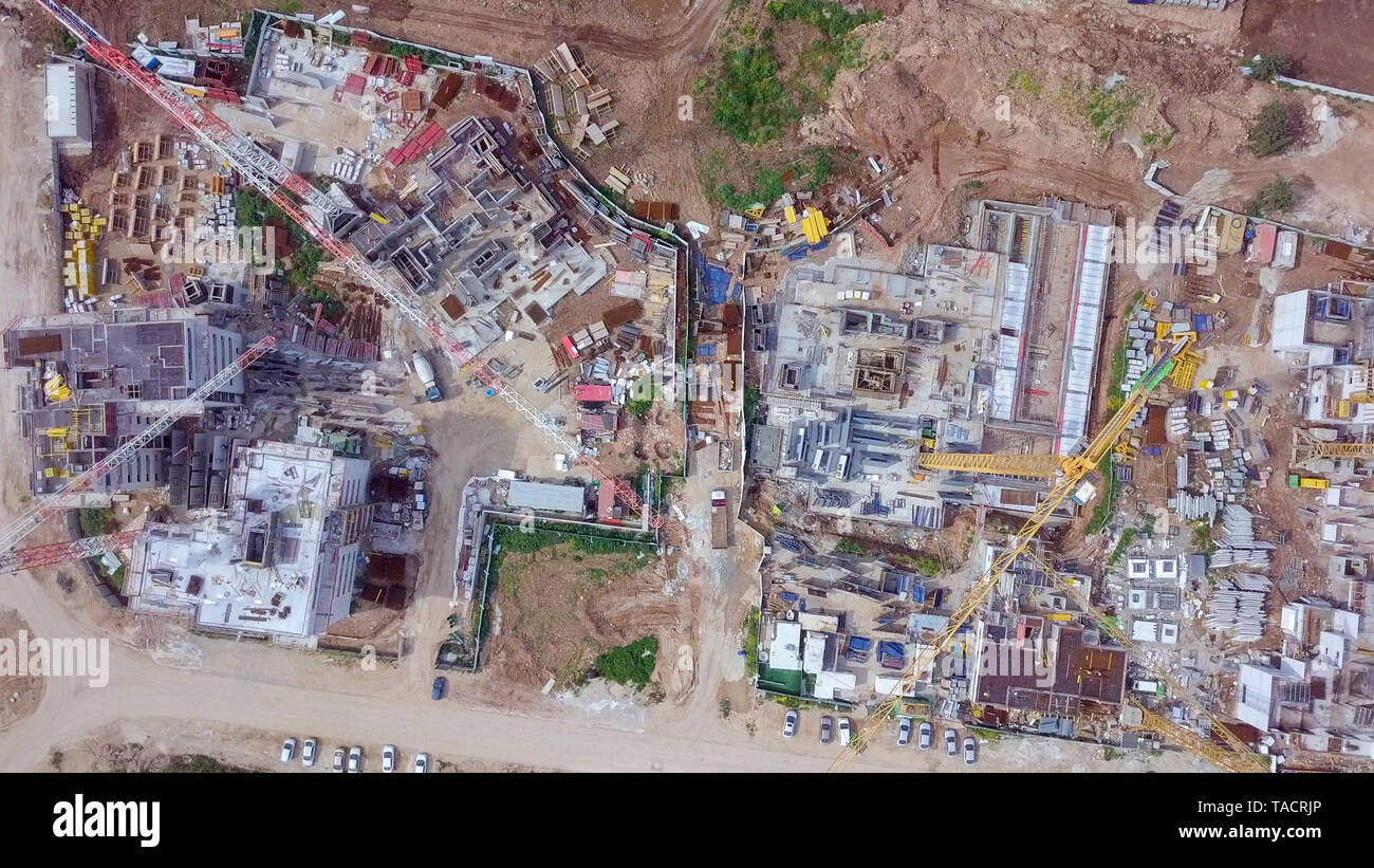 Sito in costruzione - immagine aerea di una grande zona residenziale composto durante le prime fasi di costruzione, con gru e verde ambiente circostante. Foto Stock