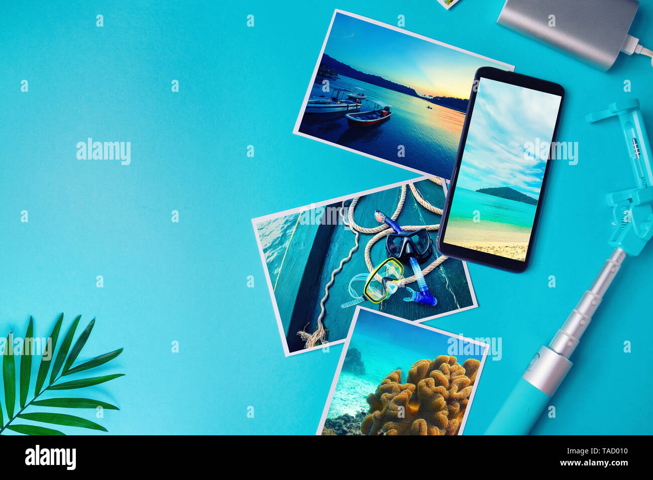 Smartphone con le foto dei tropici sullo schermo, foto con paesaggi e il mare da una vacanza su uno sfondo blu. Lay piatto. Foto Stock