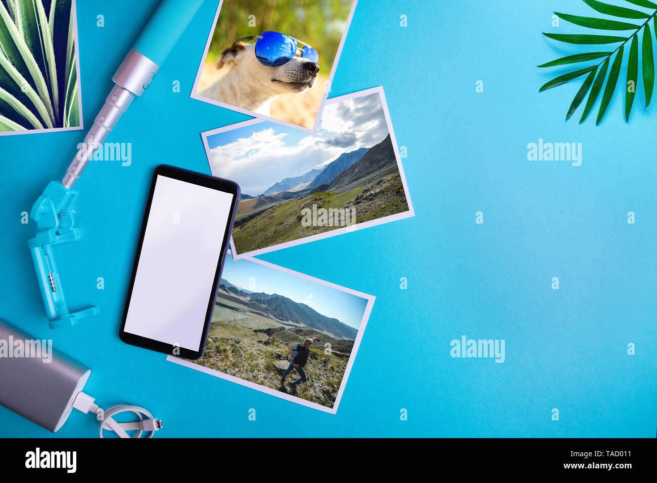 La vacanza estiva concetto. Smartphone con schermo vuoto e volantini e foto su uno sfondo blu. Mock up, laici piatta Foto Stock