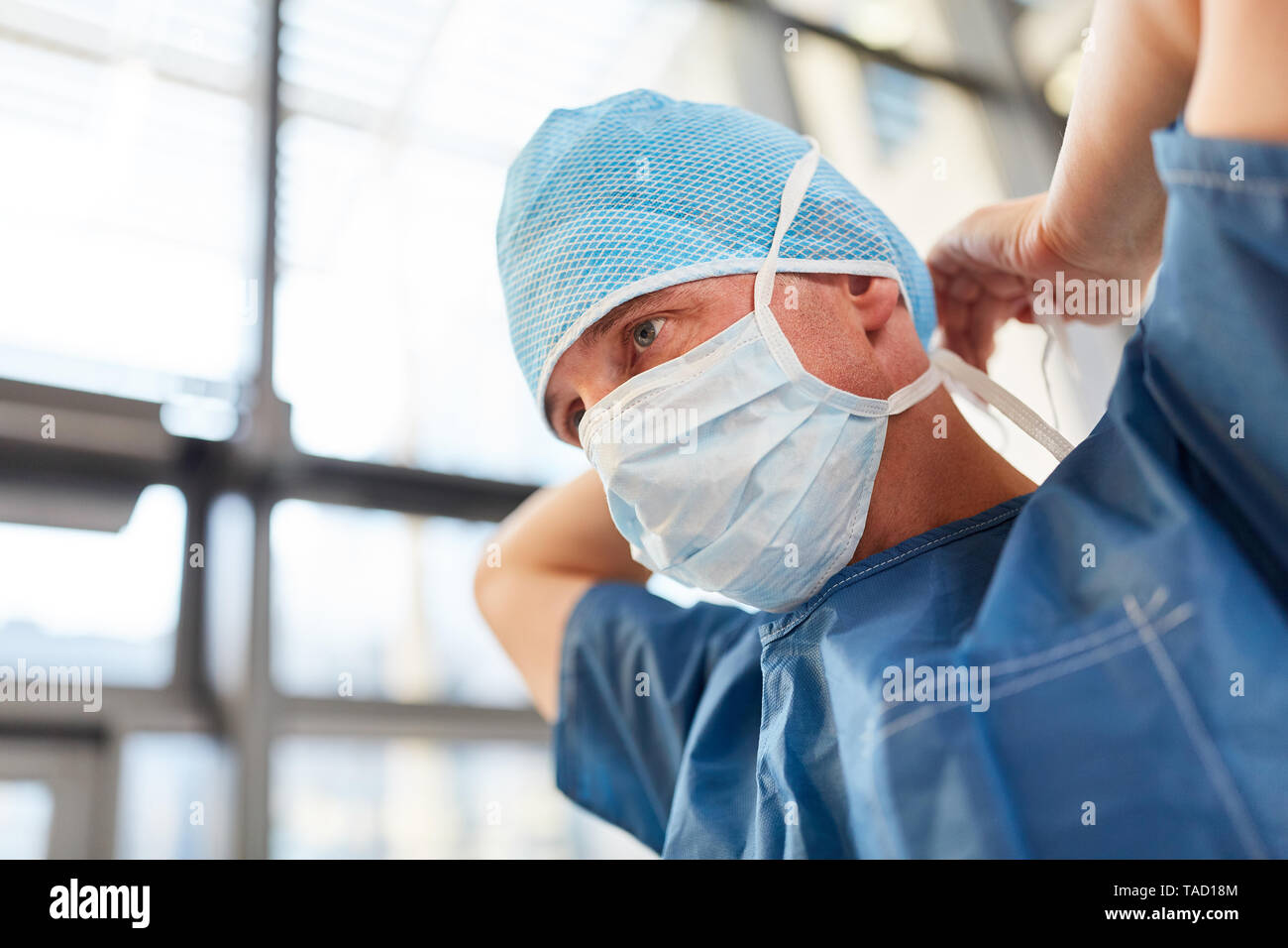 Chirurgo in blu camici chirurgici si lega il paradenti per situazioni di emergenza Foto Stock