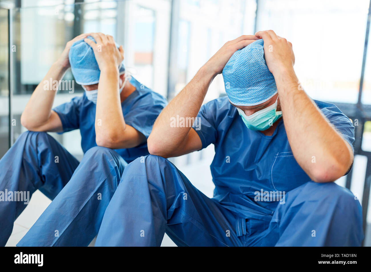 Due chirurghi esausto con le mani sui loro capi come un segno di congestione Foto Stock