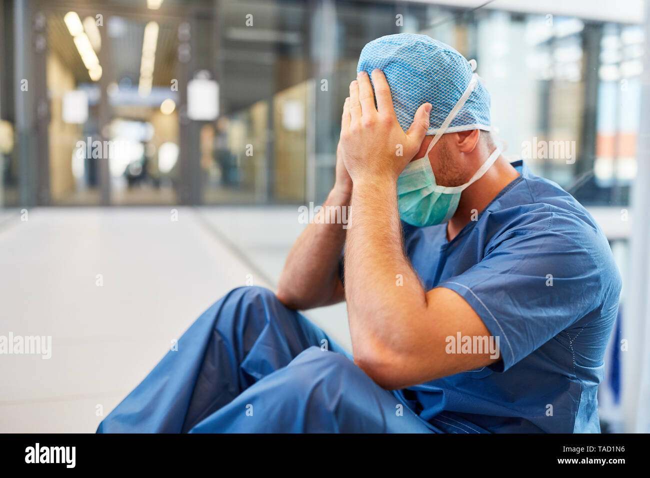 Disperato chirurgo in blu vestiti chirurgico con le mani di fronte al viso Foto Stock