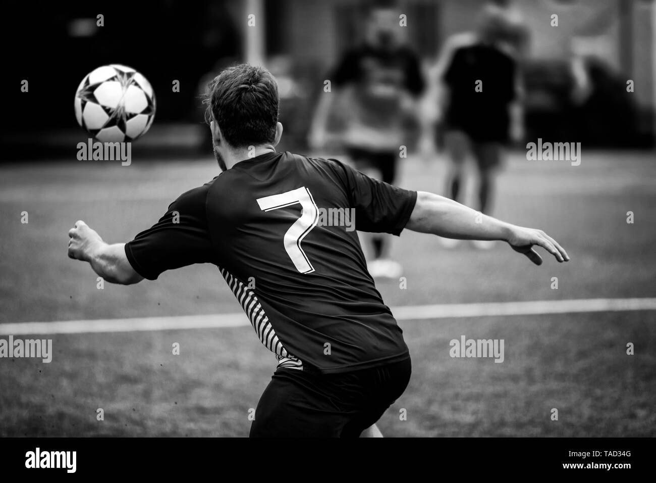 Roma, Italia - 19 Maggio 2019: giocatore di calcio in un campo di calcio insegue la palla in un gioco d'azione. Un Uomo in camicia nera e pantaloncini, incorniciato da dietro in Foto Stock
