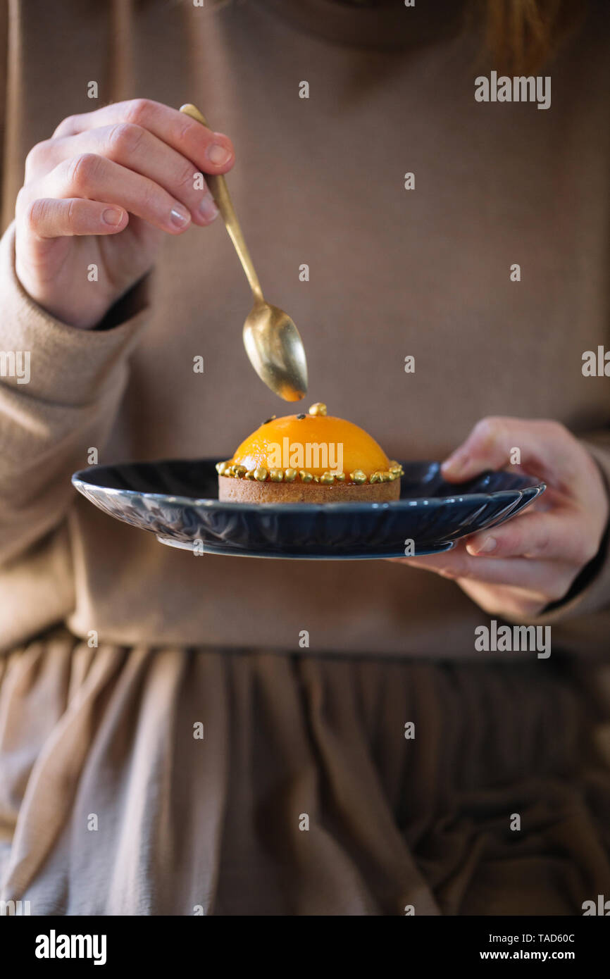 Donna di mangiare tarlet con metà di pesche, vista parziale Foto Stock