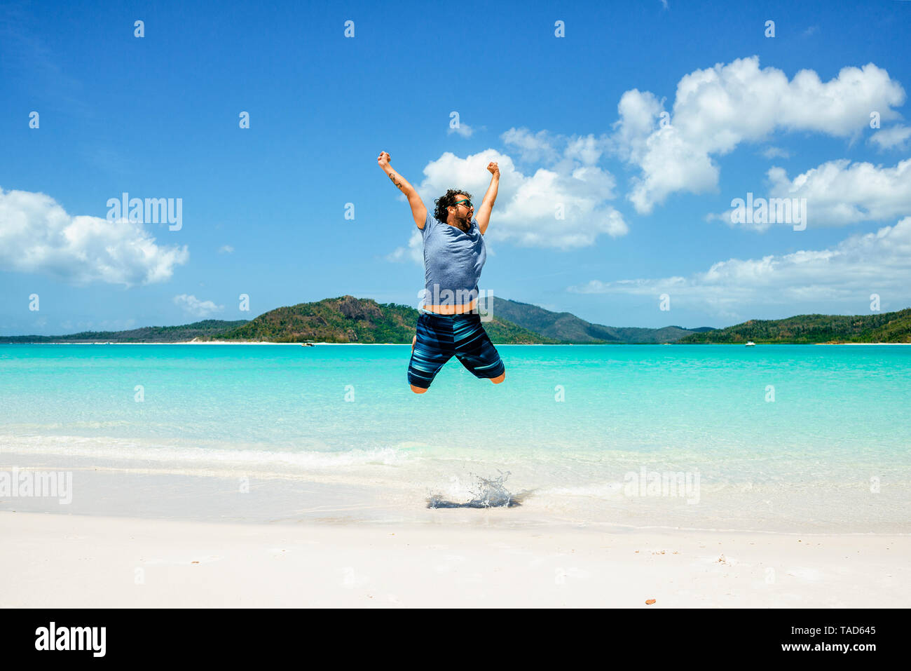 Australia, Queensland, Whitsunday Island, spensierata uomo jumping a Whitehaven Beach Foto Stock