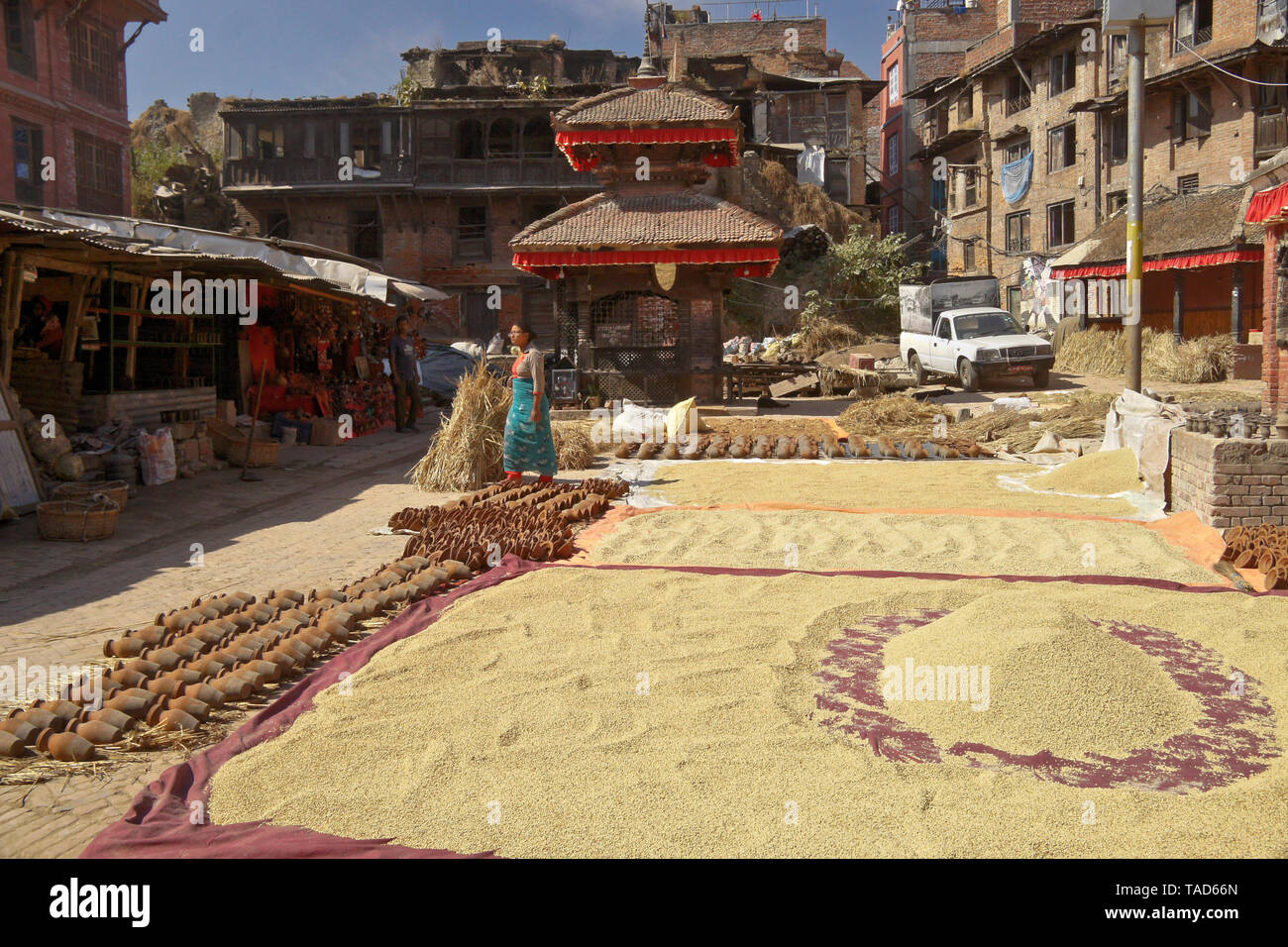 Terraglie di argilla e riso raccolto asciugando in sun accanto al santuario indù in ceramica quadrata, Bhaktapur, Valle di Kathmandu, Nepal Foto Stock