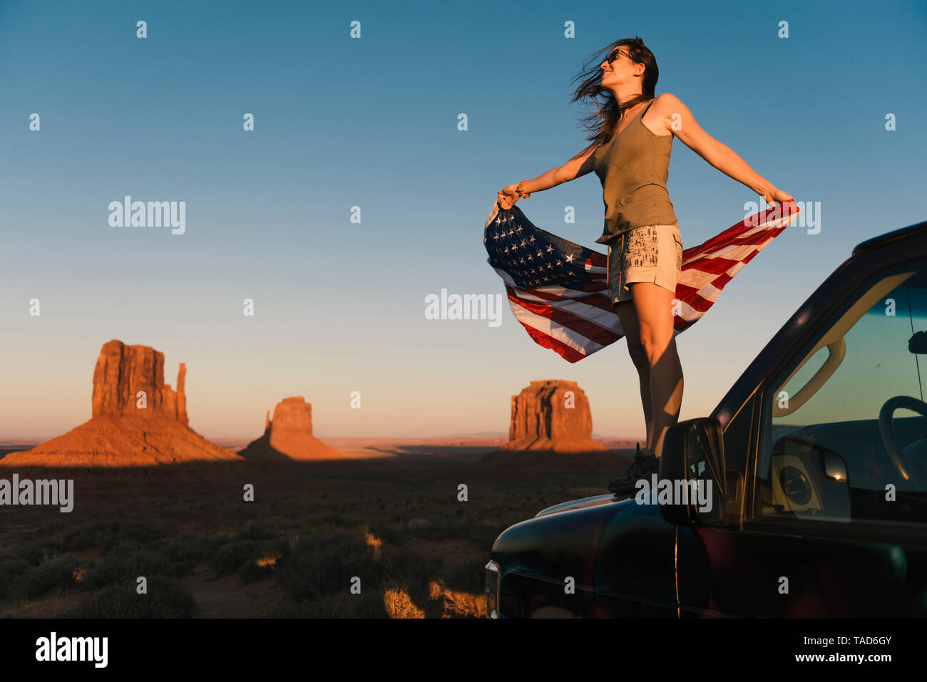 Stati Uniti d'America, Utah, Monument Valley, Donna con gli Stati Uniti d'America bandiera godendo del tramonto nella Monument Valley Foto Stock