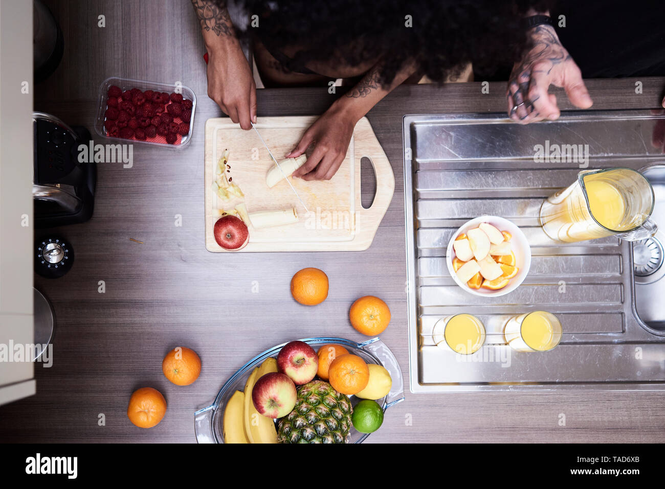 Vista superiore del giovane frutta di taglio in cucina Foto Stock