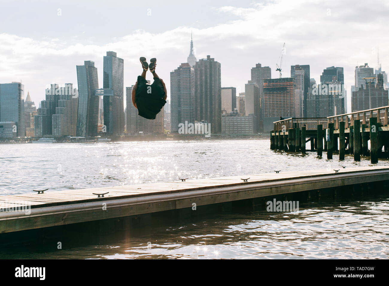 Stati Uniti d'America, New York, Brooklyn, giovani uomini facendo backflip sul molo di fronte skyline di Manhattan Foto Stock