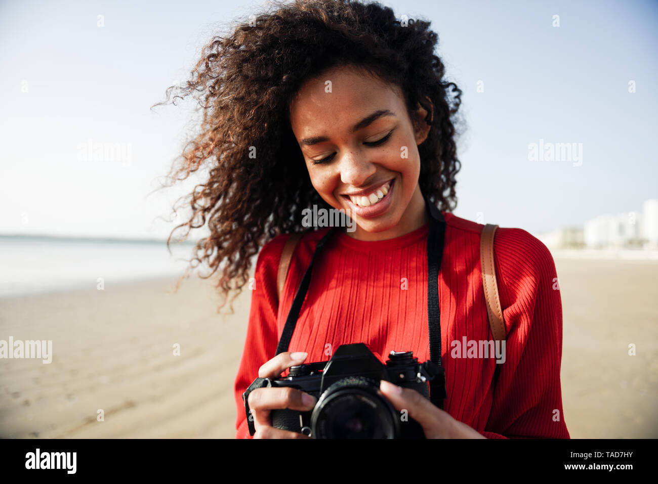 Sorridente giovane donna che guarda la fotocamera sulla spiaggia Foto Stock