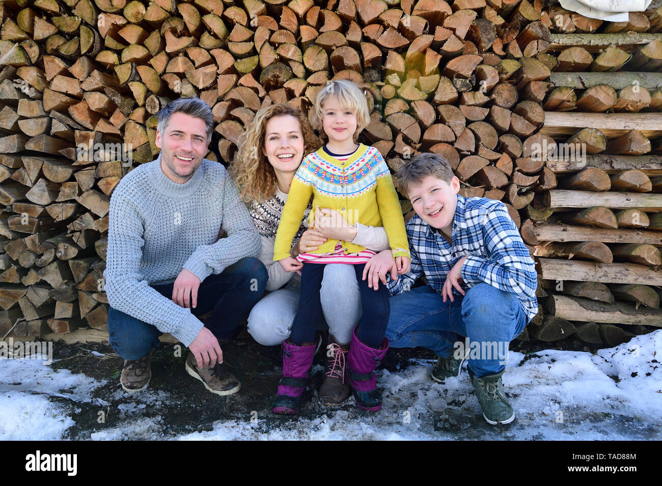 Ritratto di famiglia felice nella parte anteriore della pila di legno in inverno Foto Stock