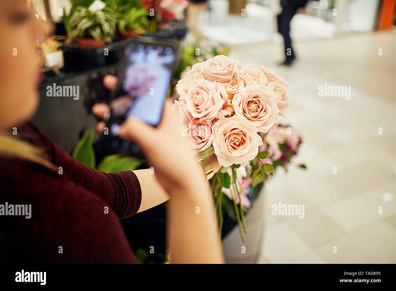 Close-up di donna holding mazzo di rose nel negozio di fiori di prendere un telefono cellulare foto Foto Stock