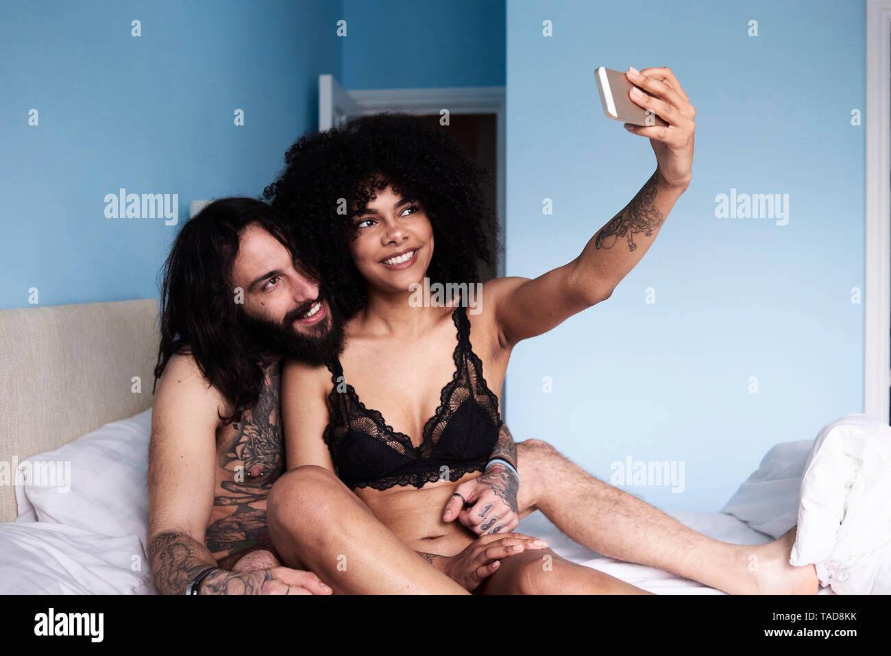 Felice affettuosa coppia giovane prendendo un selfie nel letto Foto Stock