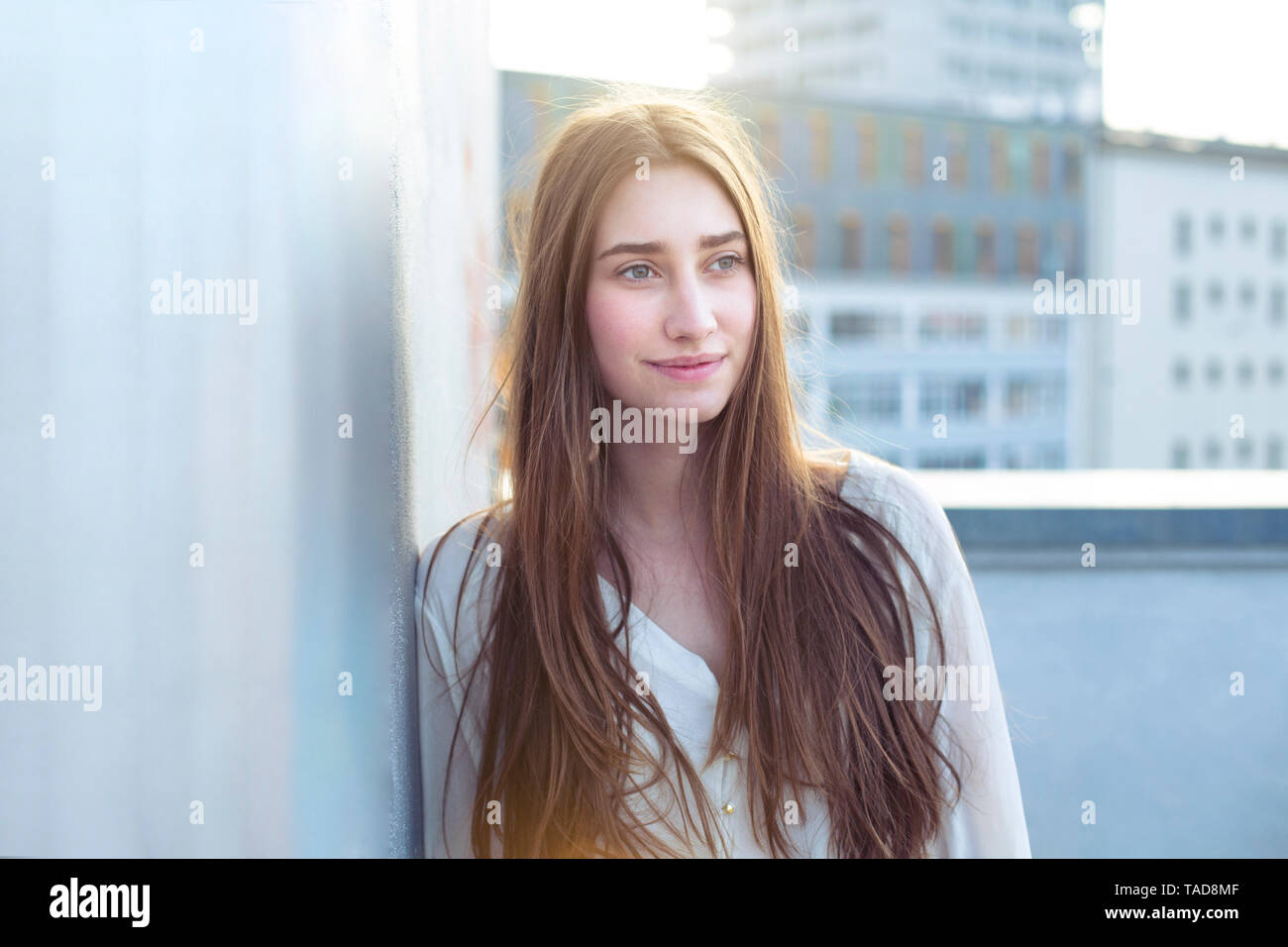 Ritratto di sorridente giovane donna appoggiata contro una parete Foto Stock
