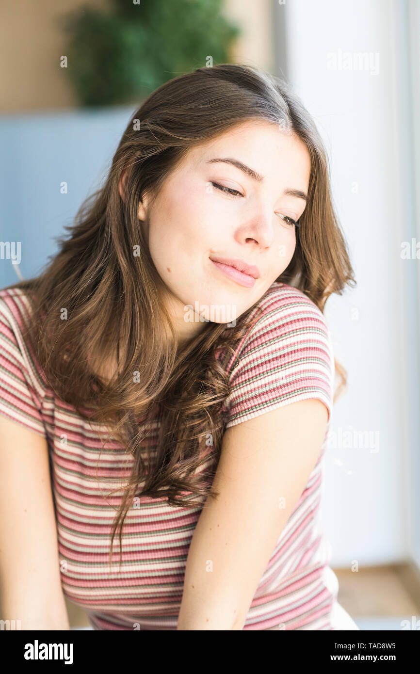 Ritratto di giovane donna a casa fantasticando Foto Stock