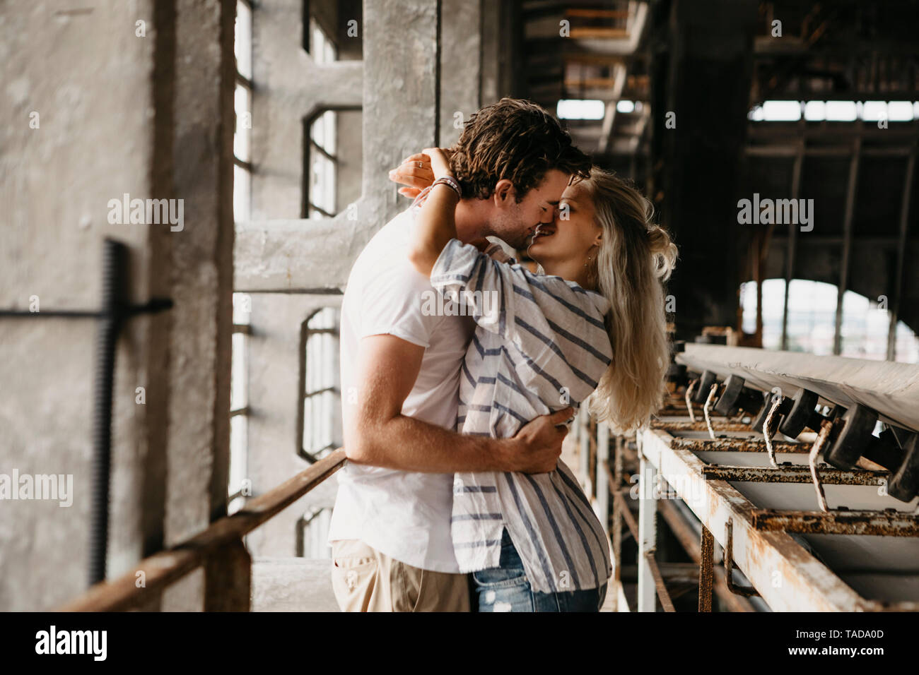 Coppia giovane baciare in una vecchia stazione ferroviaria Foto Stock