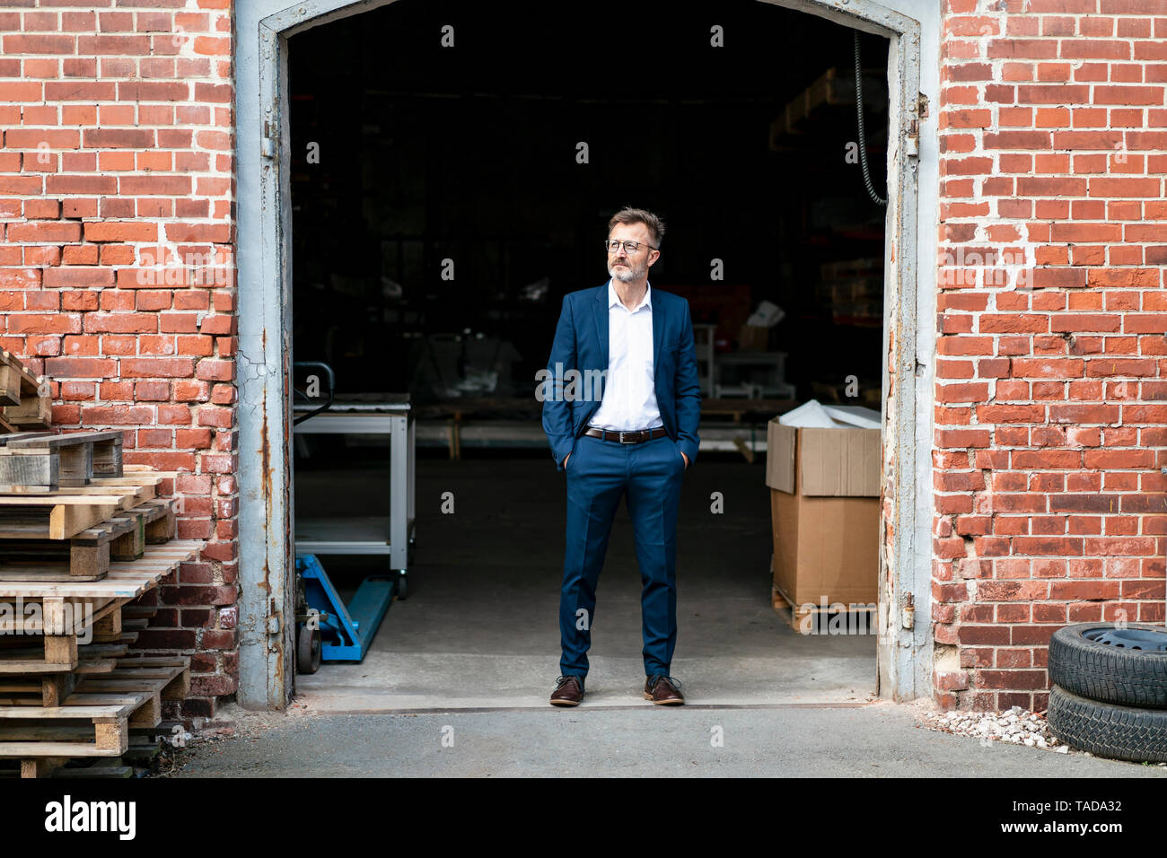 Imprenditore permanente al vecchio magazzino guardando lontano Foto Stock
