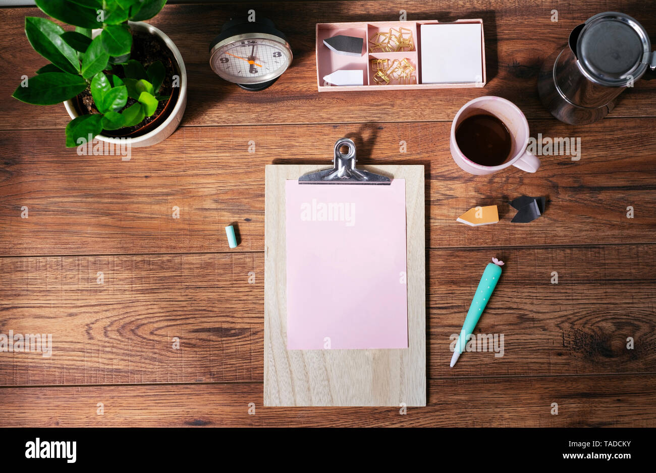 Clip board con vuoto carta rosa, tazza da caffè e altri utensili sulla scrivania in ufficio in casa vista superiore Foto Stock