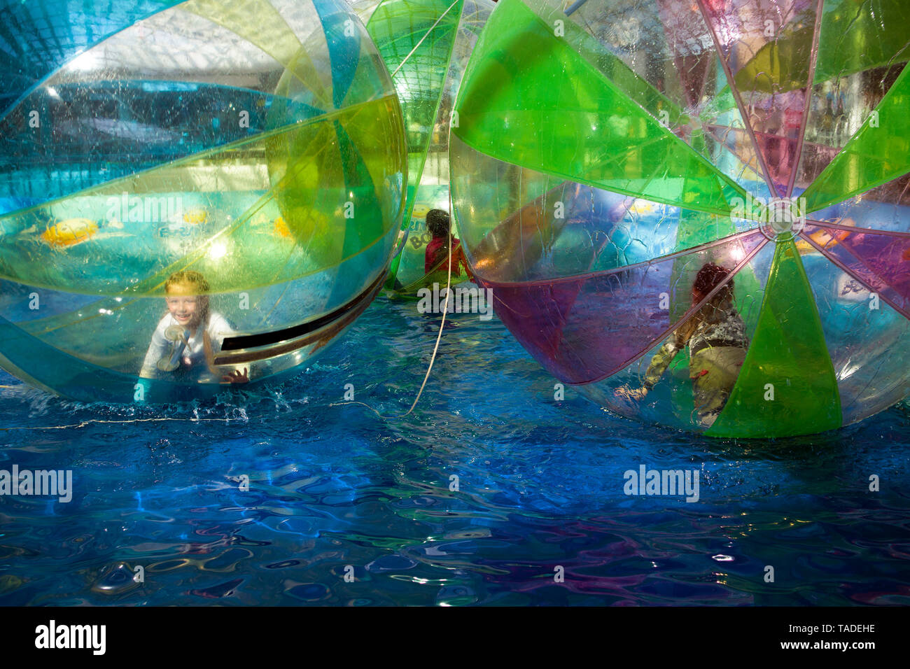 Bambina gioca dentro le grandi acque trasparenti di bolla in piscina Foto Stock