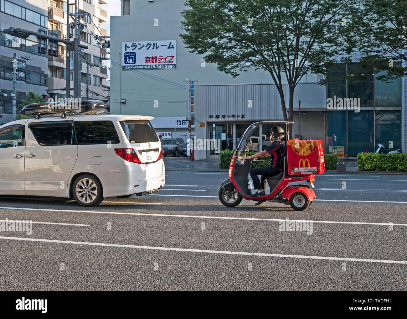 McDonalds driver di consegna su uno scooter rosso su una strada di Tokyo, Giappone. Foto Stock