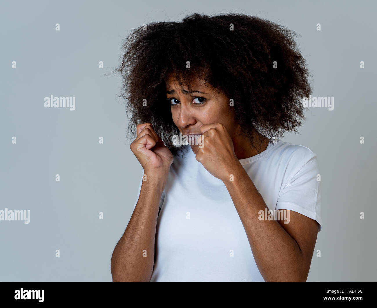 Ritratto di giovane americano africano sentimento donna spaventato e scioccato rendendo la paura, ansia gesti. Guardando terrorizzata la copertura stessa. Copia dello spazio. In Foto Stock