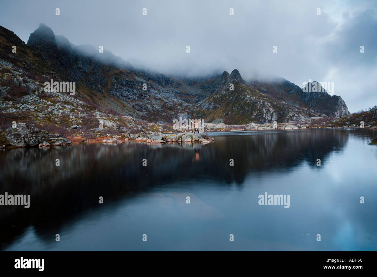 Norvegia Isole Lofoten Henningsvaer, uomo in piedi alla riva del mare con i bracci sollevati Foto Stock