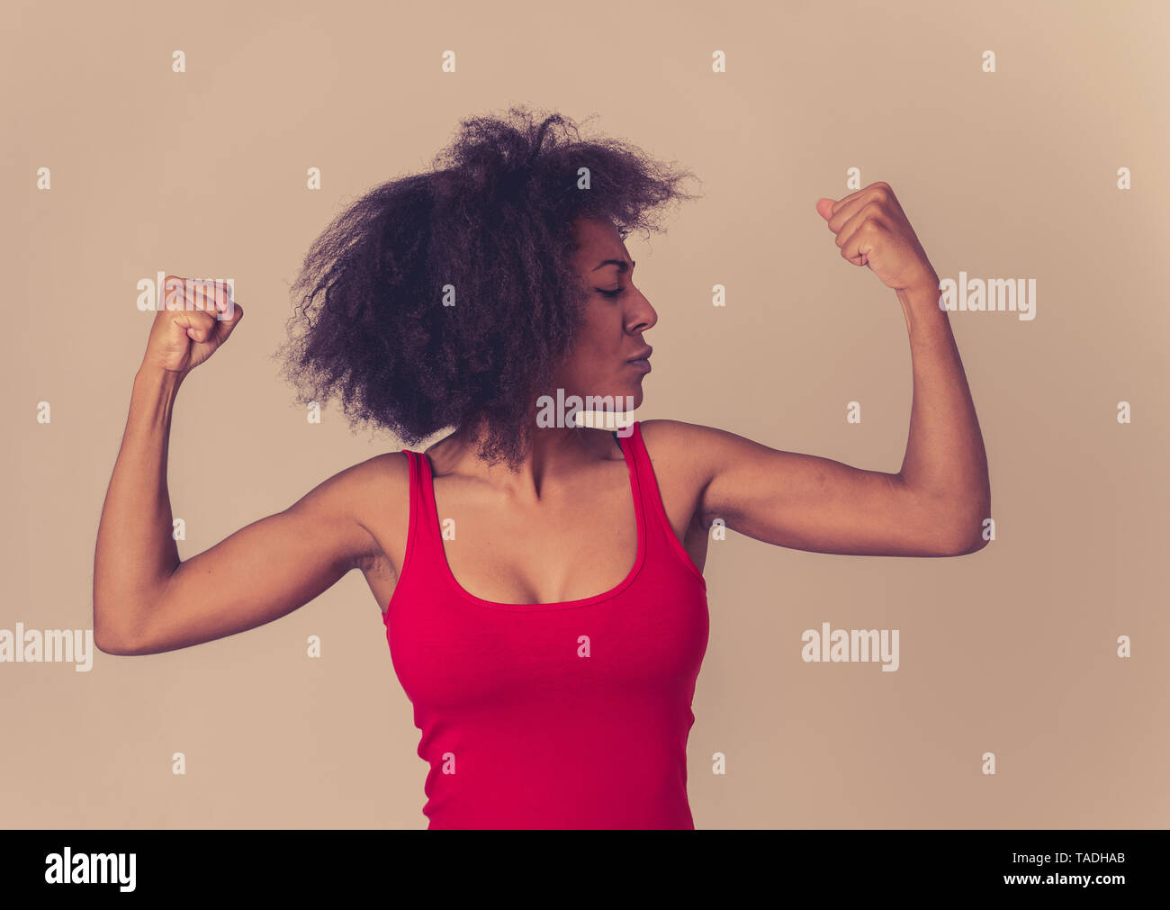 Ritratto di giovane bella funny african american donna con capelli afro style che mostra i muscoli di armi sorridente orgogliosi di divertimento. Nelle persone di successo e Hap Foto Stock