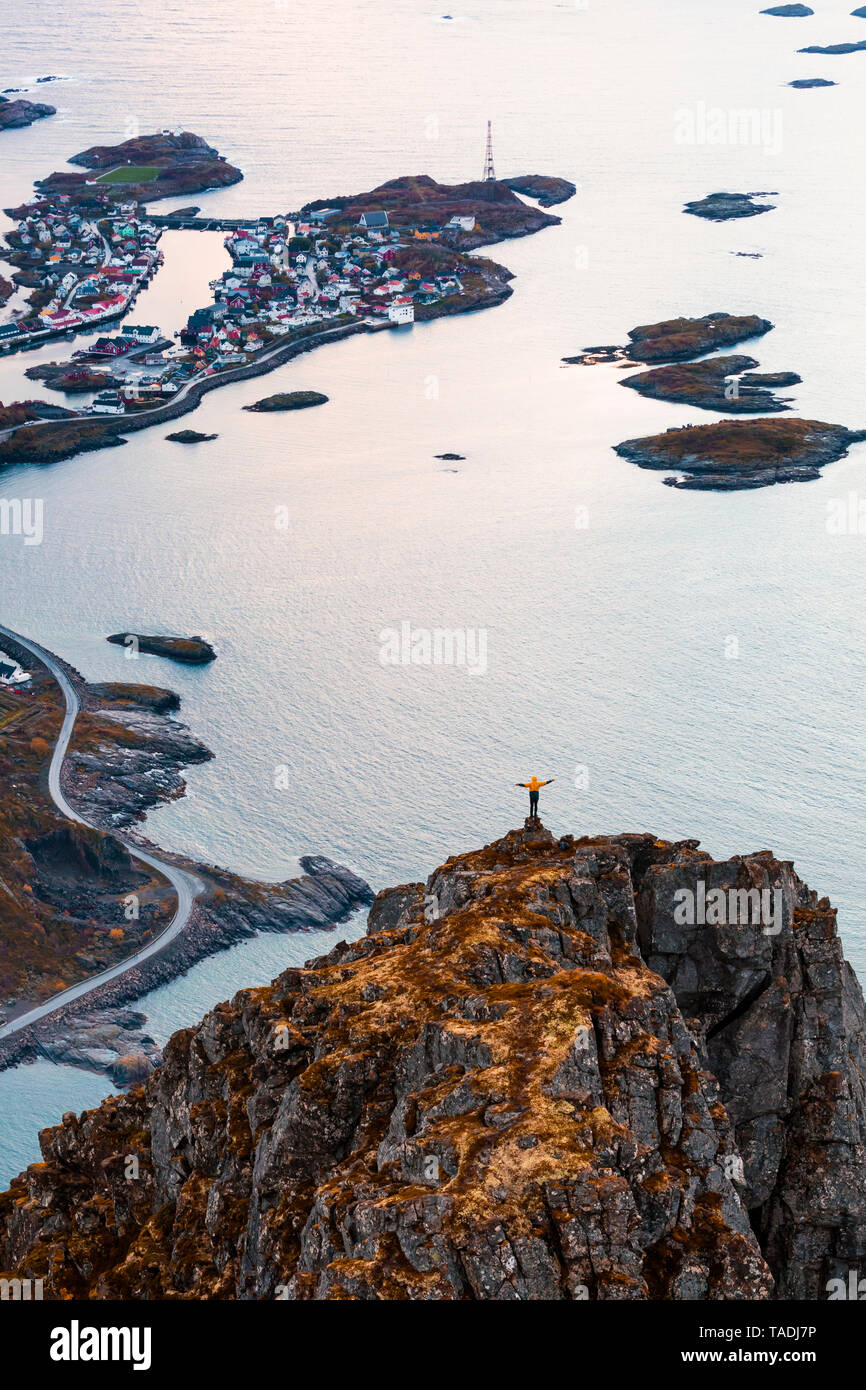 Norvegia Isole Lofoten Henningsvaer, uomo in piedi sul punto di visualizzazione con i bracci di sollevamento Foto Stock